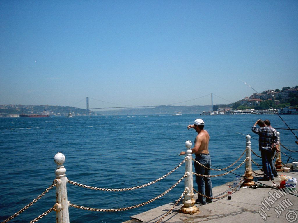 View of fishing people and on the horizon Bosphorus Bridge from Uskudar shore of Istanbul city of Turkey.
